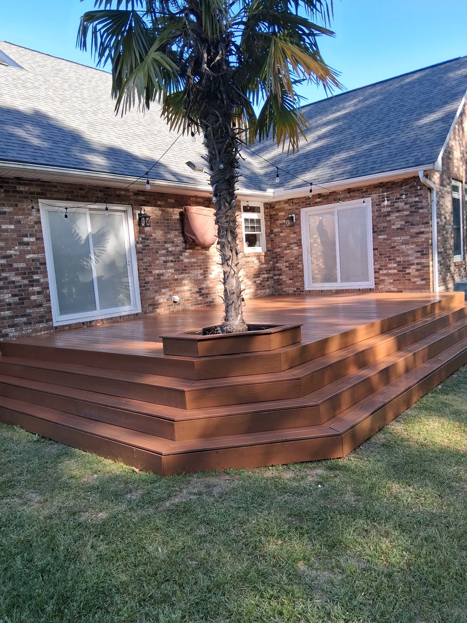Multi-level composite deck with stepped design and built-in planter, brick home exterior