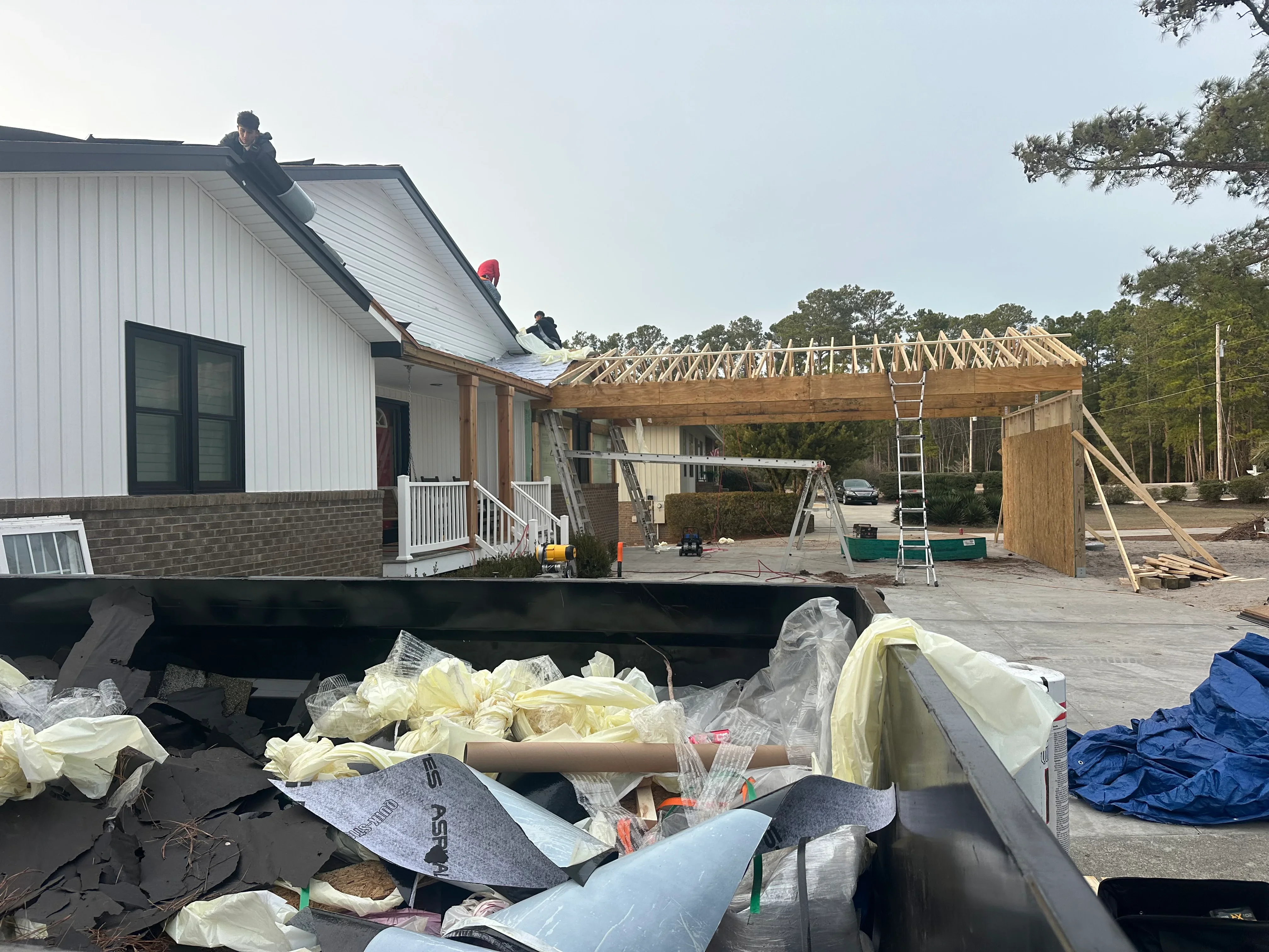 Metal roof installation and timber addition framing on residential home with workers on roof