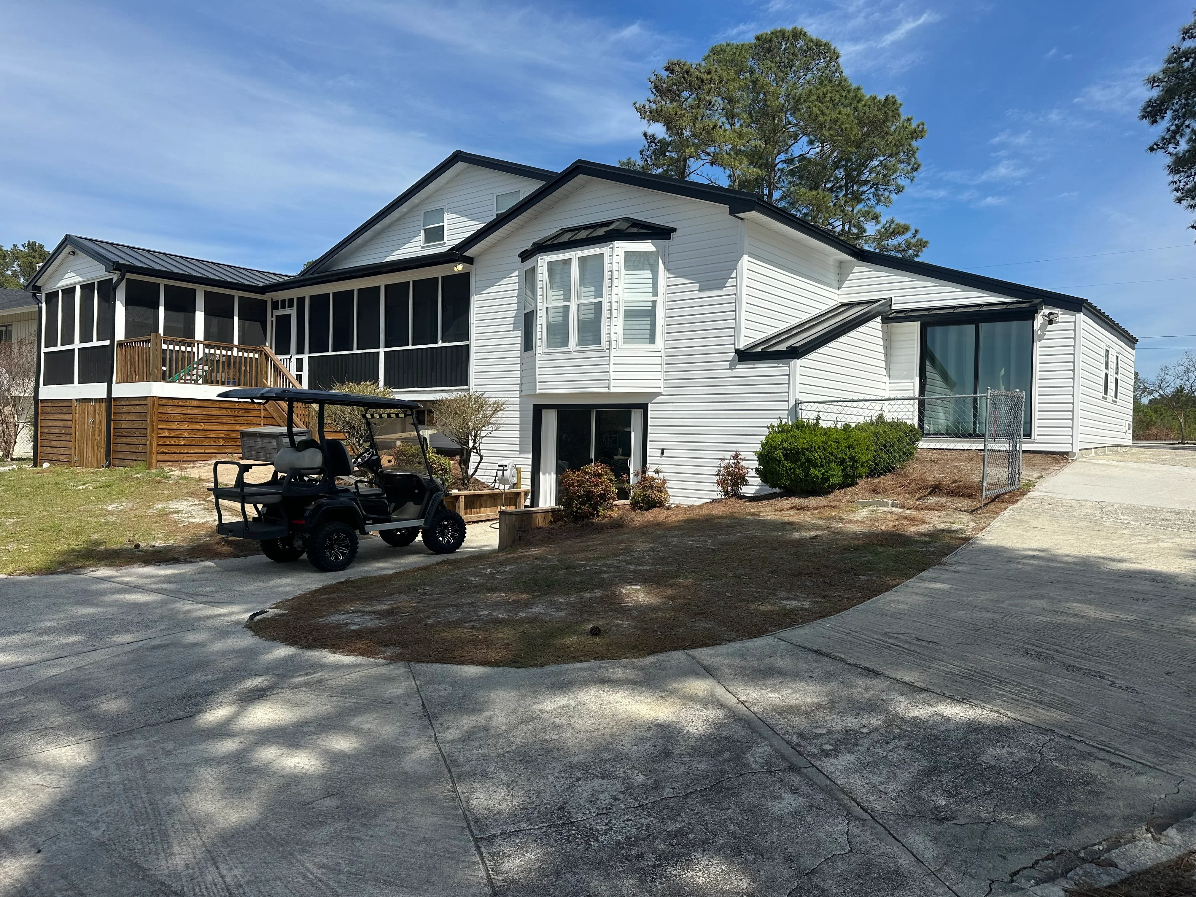 White vinyl sided home with new black roof shingles, screened porch, and concrete driveway