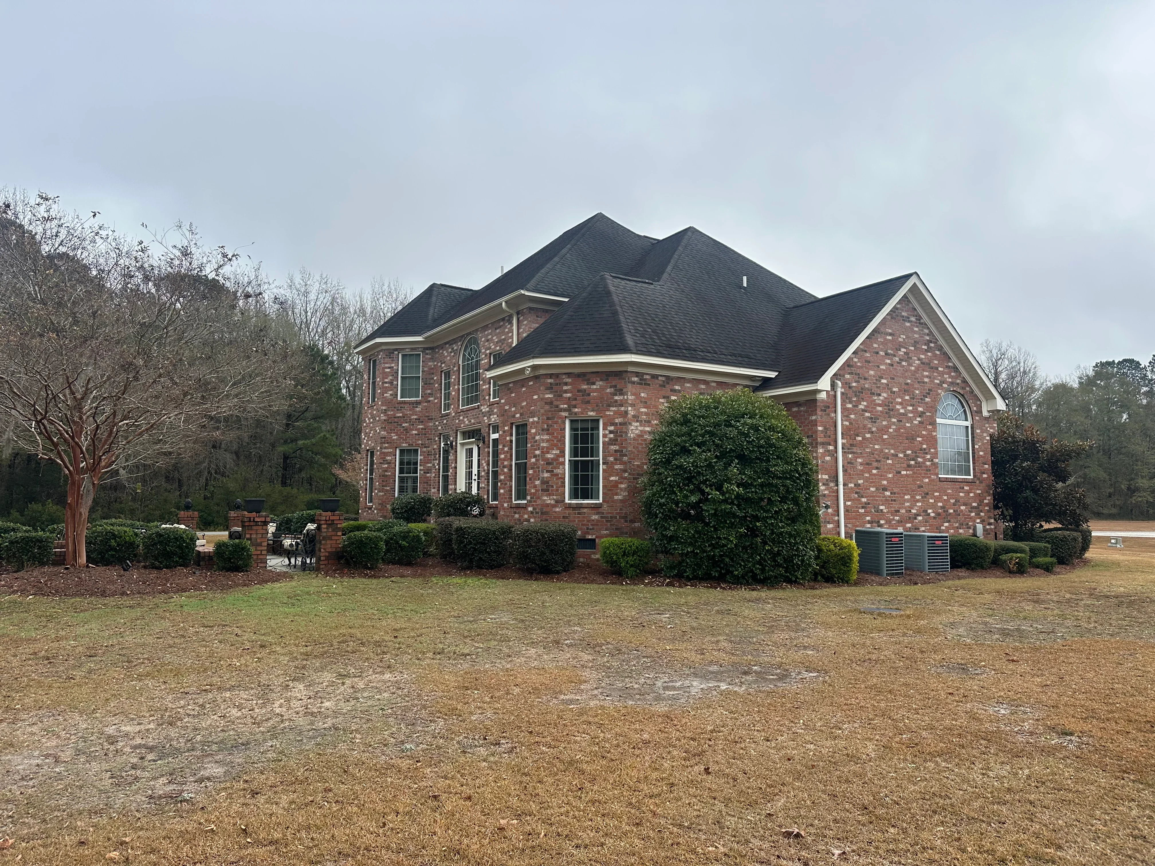 Two-story brick home with new charcoal gray architectural shingle roof and multi-peak design